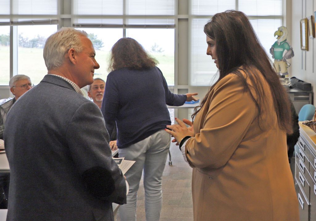 Two people speak in the foreground with three others speaking in the background.