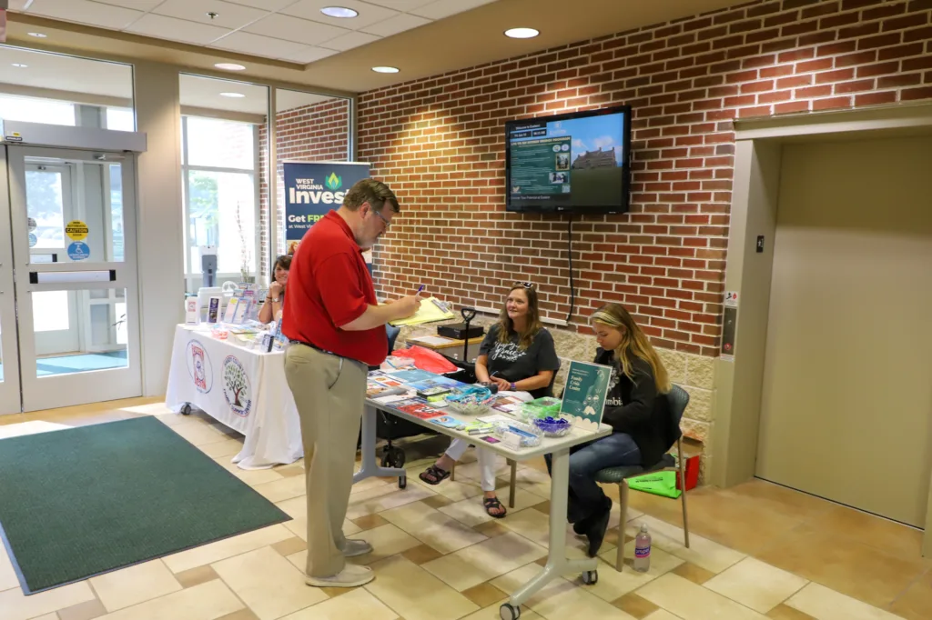 Man standing in front of table with two women sitting at it