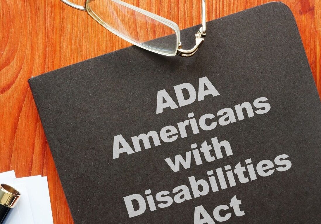 Photo of a notebook, glasses and a pen. The notebook cover reads, "ADA Americans with Disabilities Act."