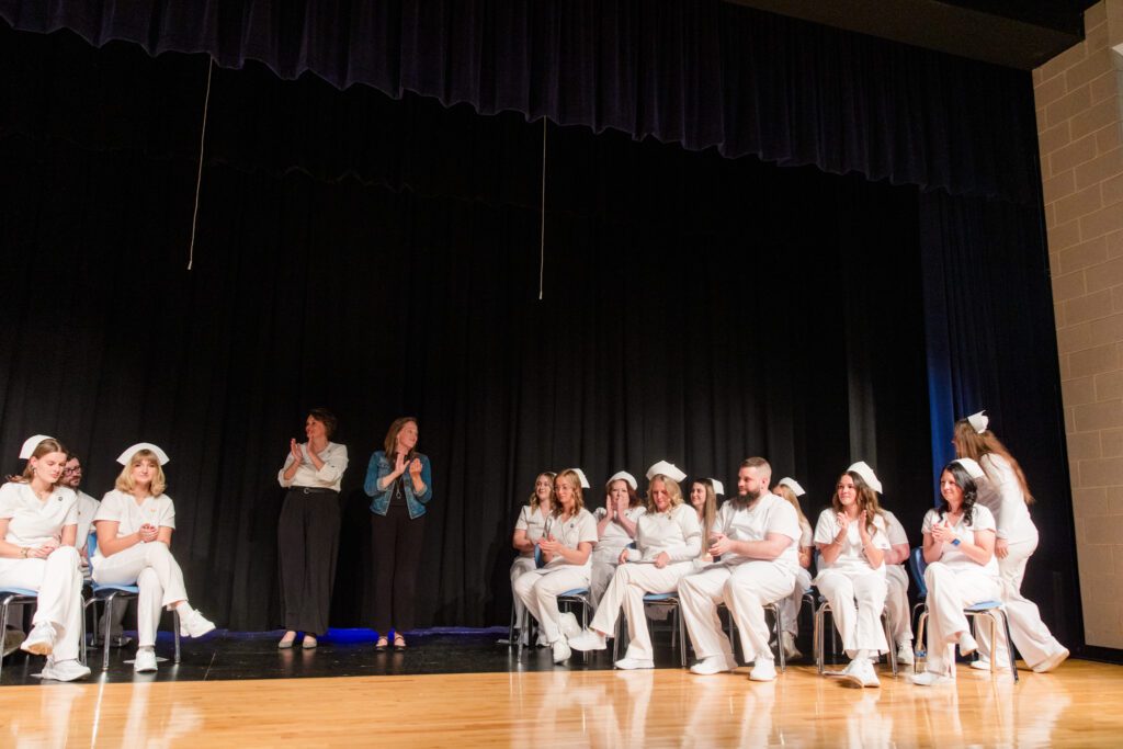 Photo of a group of nursing students separated into two sections and the instructors in the middle.